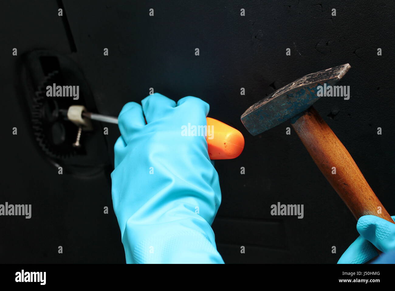 Technician wear rubber grove to use hammer to hit screwdriver for