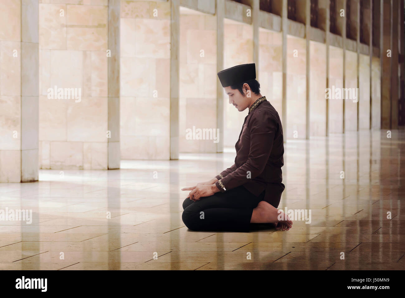 Religious asian muslim man with black cap praying in the mosque Stock Photo