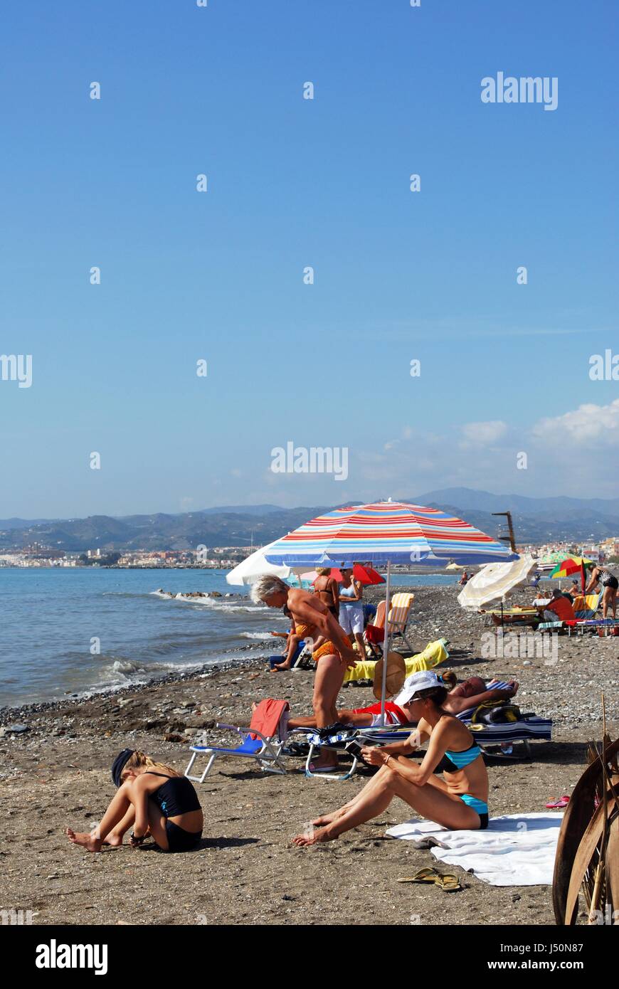 Tourists relaxing on the pebble beach, Lagos, Malaga Province, Andalusia, Spain, Western Europe. Stock Photo