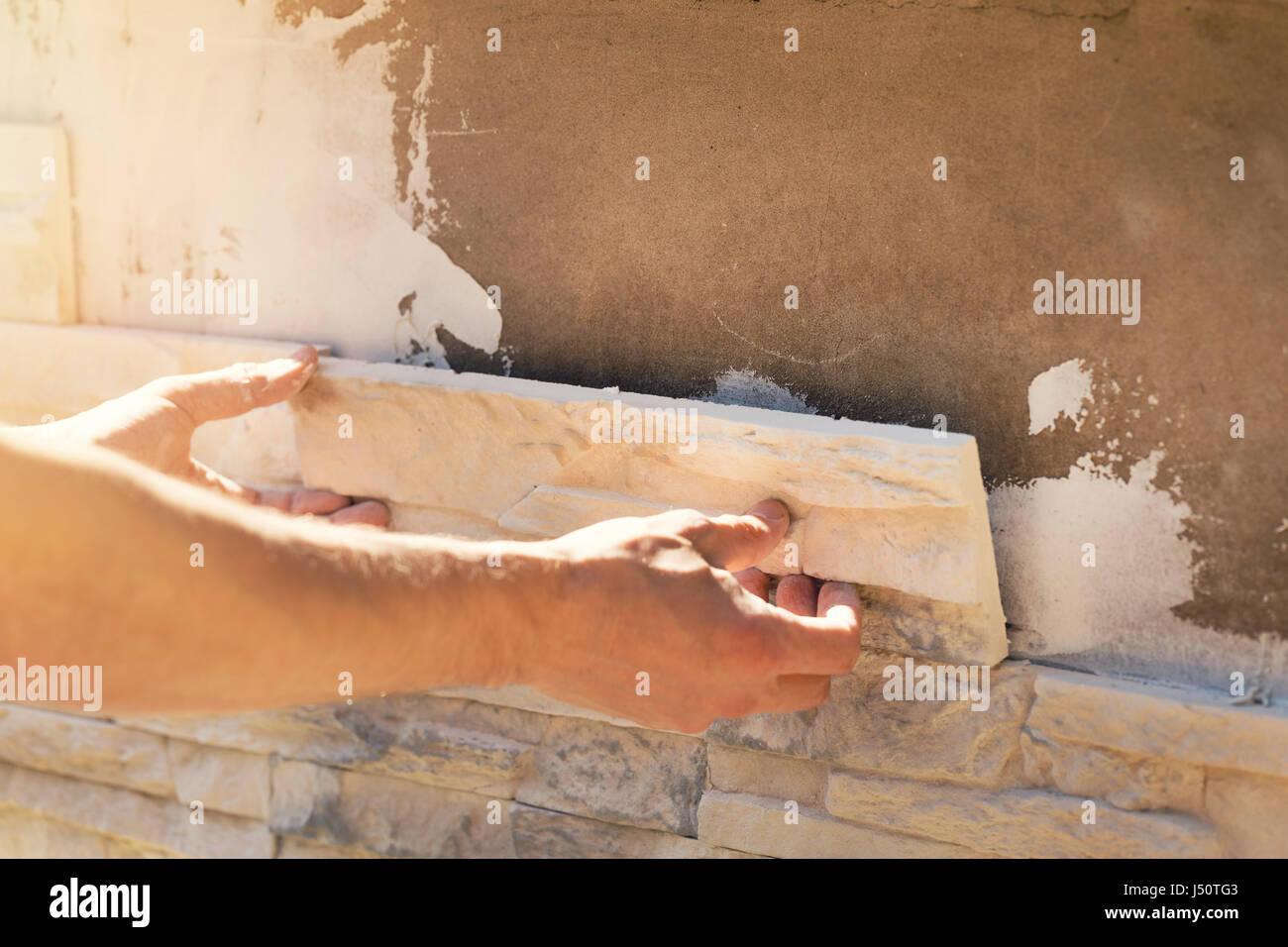 worker installing decorative stone tiles on house facade Stock Photo