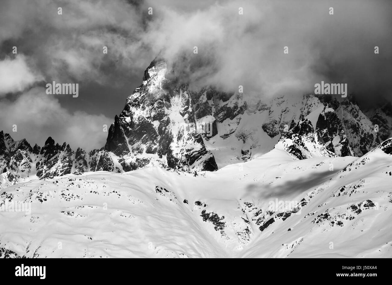 Black and white view on mount Ushba in fog at sun winter day before storm. Caucasus Mountains. Svaneti region of Georgia. Stock Photo