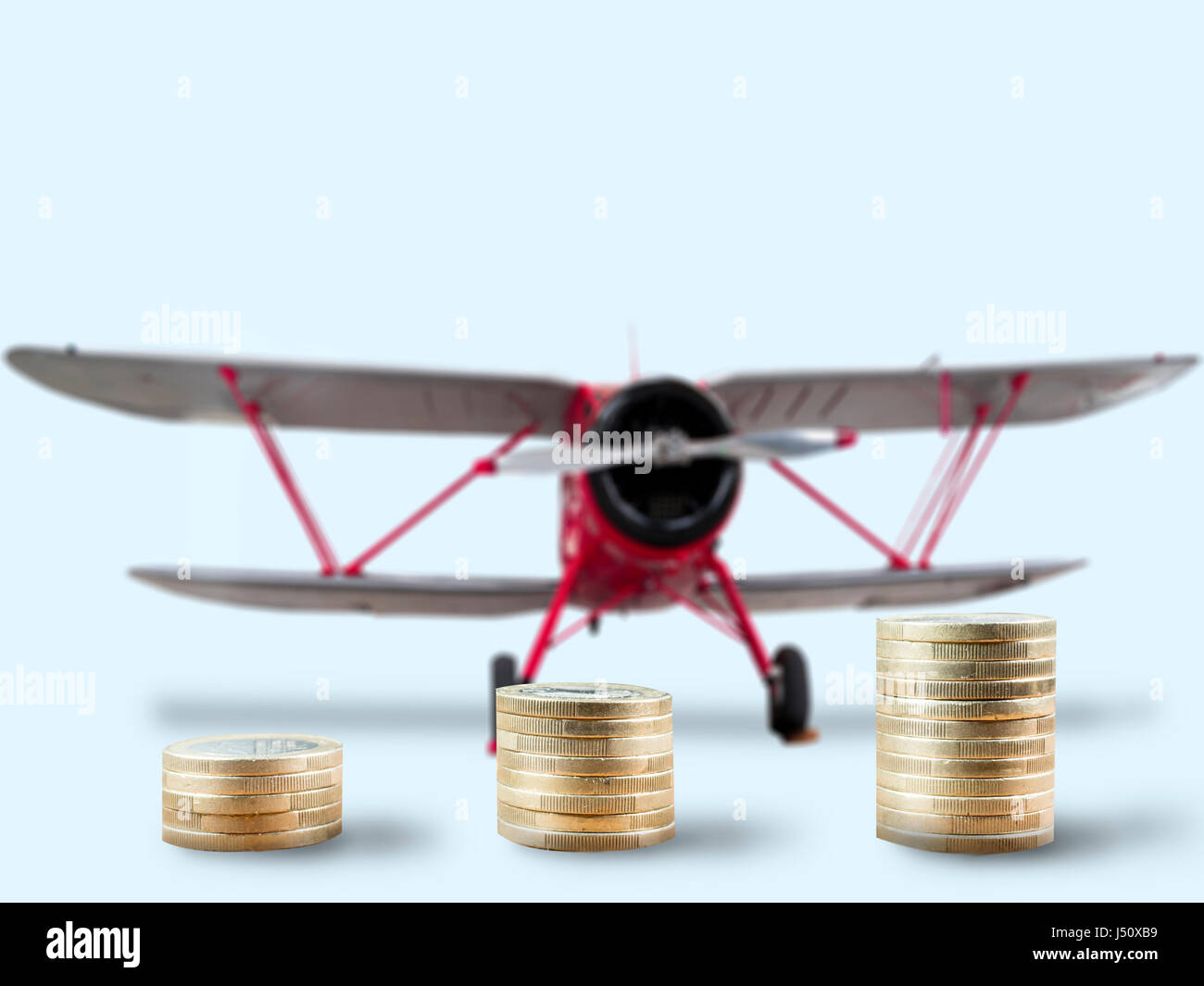 coin stacks in front of classic aircraft Stock Photo
