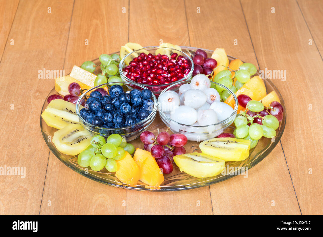 Glass scale with various fresh summer fruits on wooden floor Stock Photo