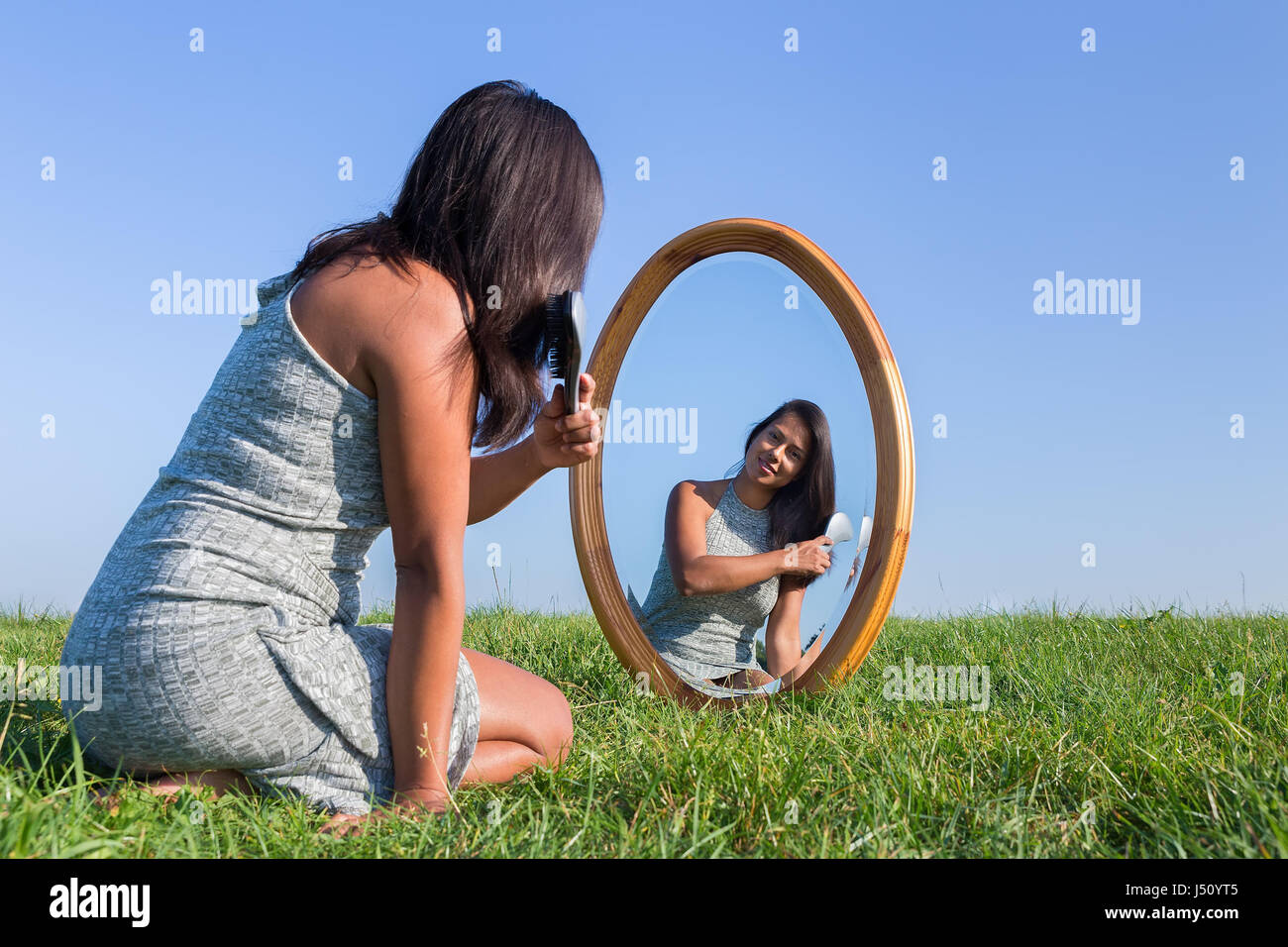 Colombian woman brushing her black hair in mirror outdoors Stock Photo