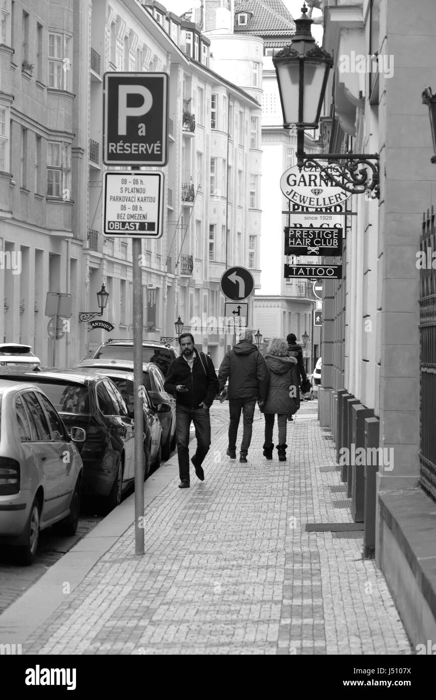 Pedestrians walking past a jewelers and a tattoo parlor on a quiet side street in the city of Prague in April 2017. Stock Photo