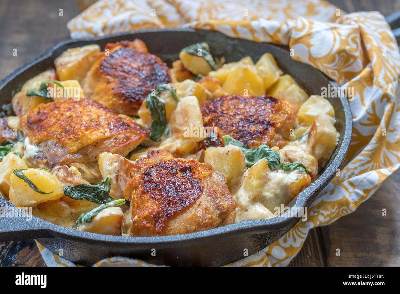Roast chicken, potatoes and spinach with creamy sauce in a frying pan