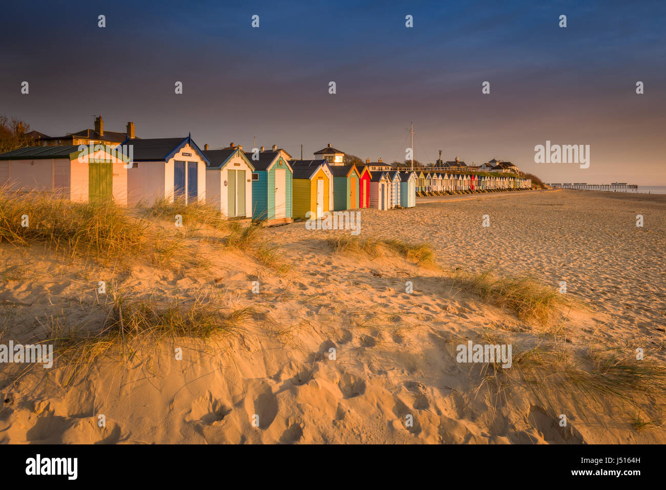 After a cold clear night, there's a beautiful sunrise over the famous line of beach huts on the dunes at the Suffolk seaside town of Southwold. Stock Photo