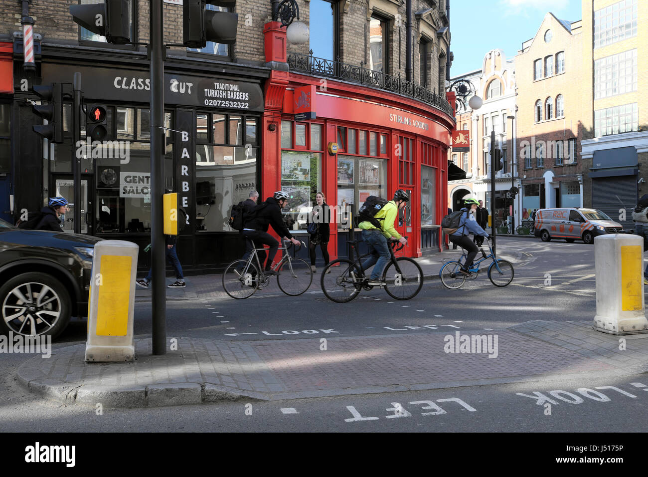 People cycling to work cycle past small shops on the corner of St John Street and Clerkenwell Road in London EC1 England UK   KATHY DEWITT Stock Photo