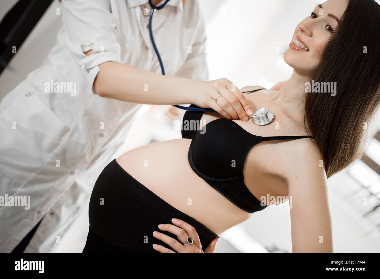 female medicine doctor holding stethoscope to pregnant woman standing for encouragement, empathy, cheering,support, medical examination. New life of abortion concept. Stock Photo