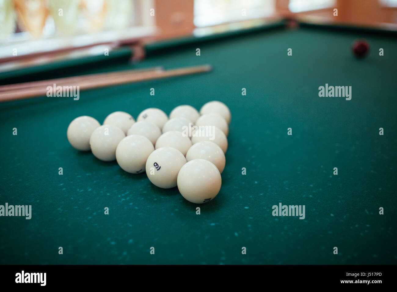 Billiard balls and two Cues in the form of a triangle on the billiard table are ready for the game. Stock Photo