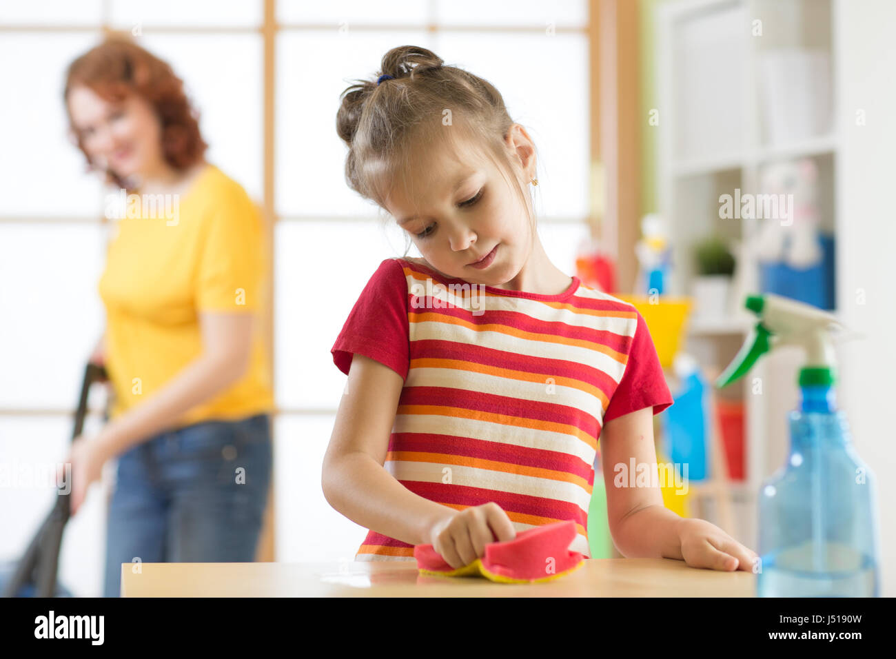 Mother and daughter cleaning in living room Stock Photo