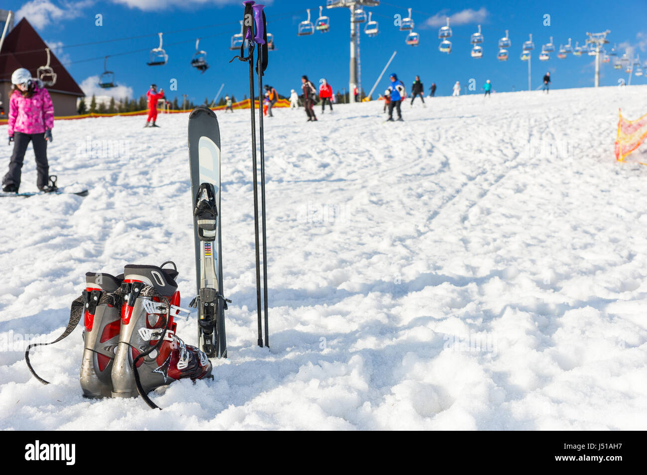 View of red and gray boots next to ski laying in fluffy snow in a ski ...