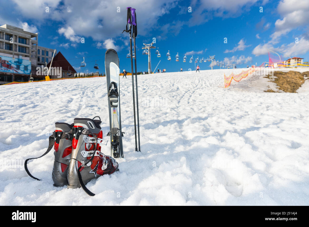 Red and gray boots next to ski laying in fluffy snow in a ski-resort in ...