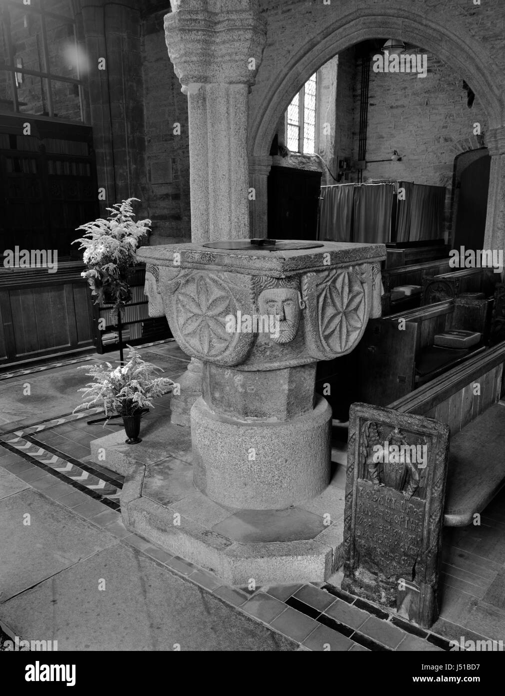 St Nonna's Church, Altarnun, Cornwall: C12th Norman carved granite font and a C16th (1510-1530) wooden bench end carved & signed by Robert (sic) Daye. Stock Photo