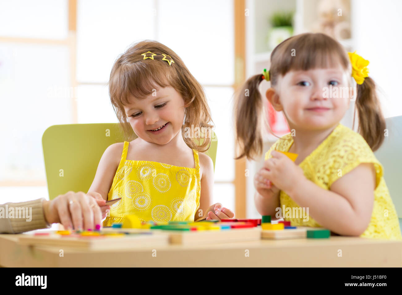 Kids children girls playing with educational child toys at home or daycare centre. Stock Photo