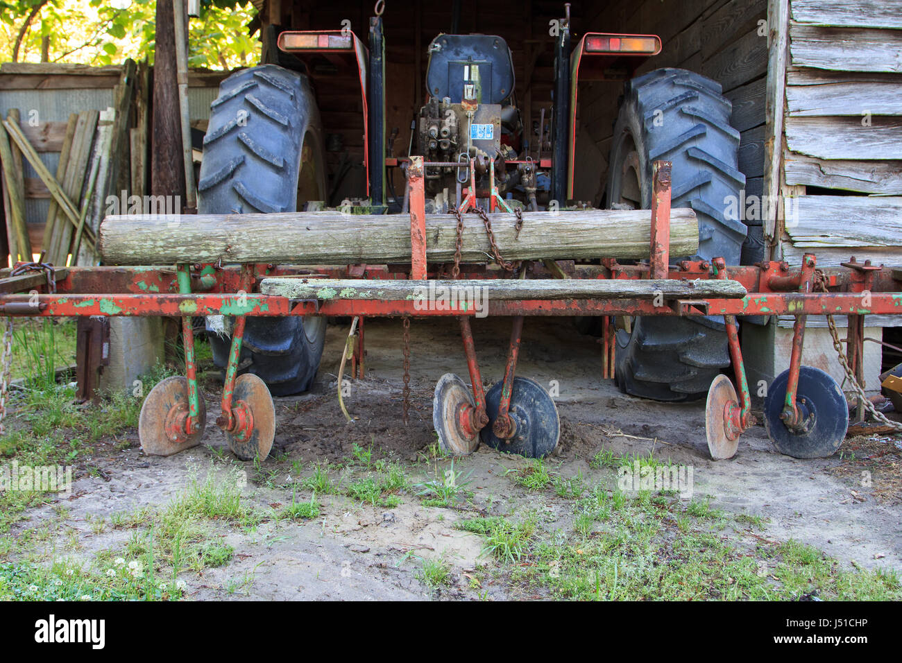Tractor with disk harrow plow in dilapidated barn Stock Photo