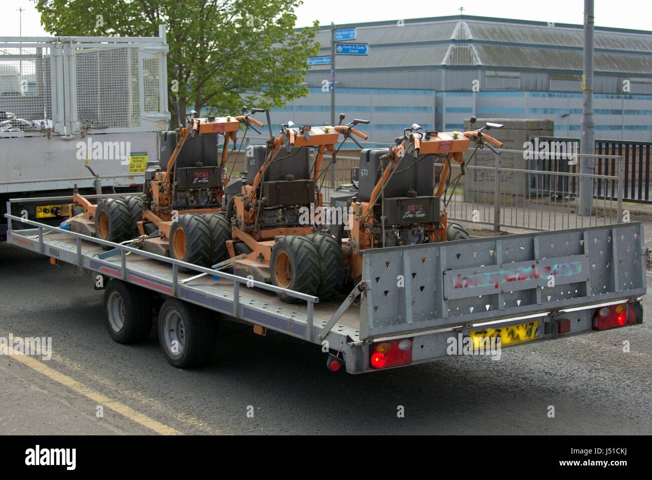 industrial mechanical grass cutters being transported on the back of lorry or truck Stock Photo