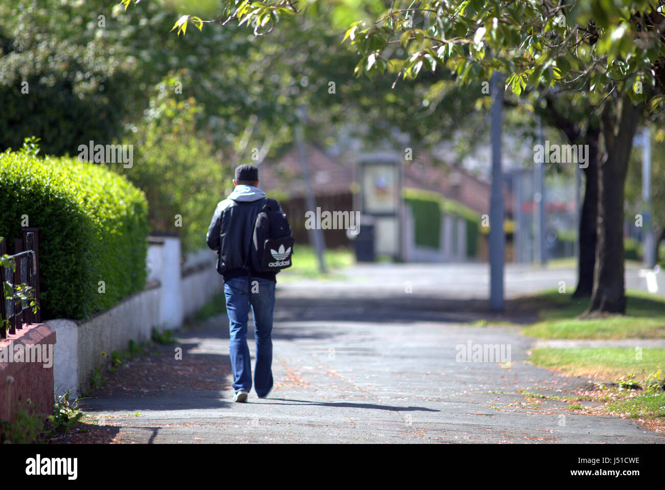 Single man with backpack rucksack on pavement Glasgow street walking pedestrian Stock Photo