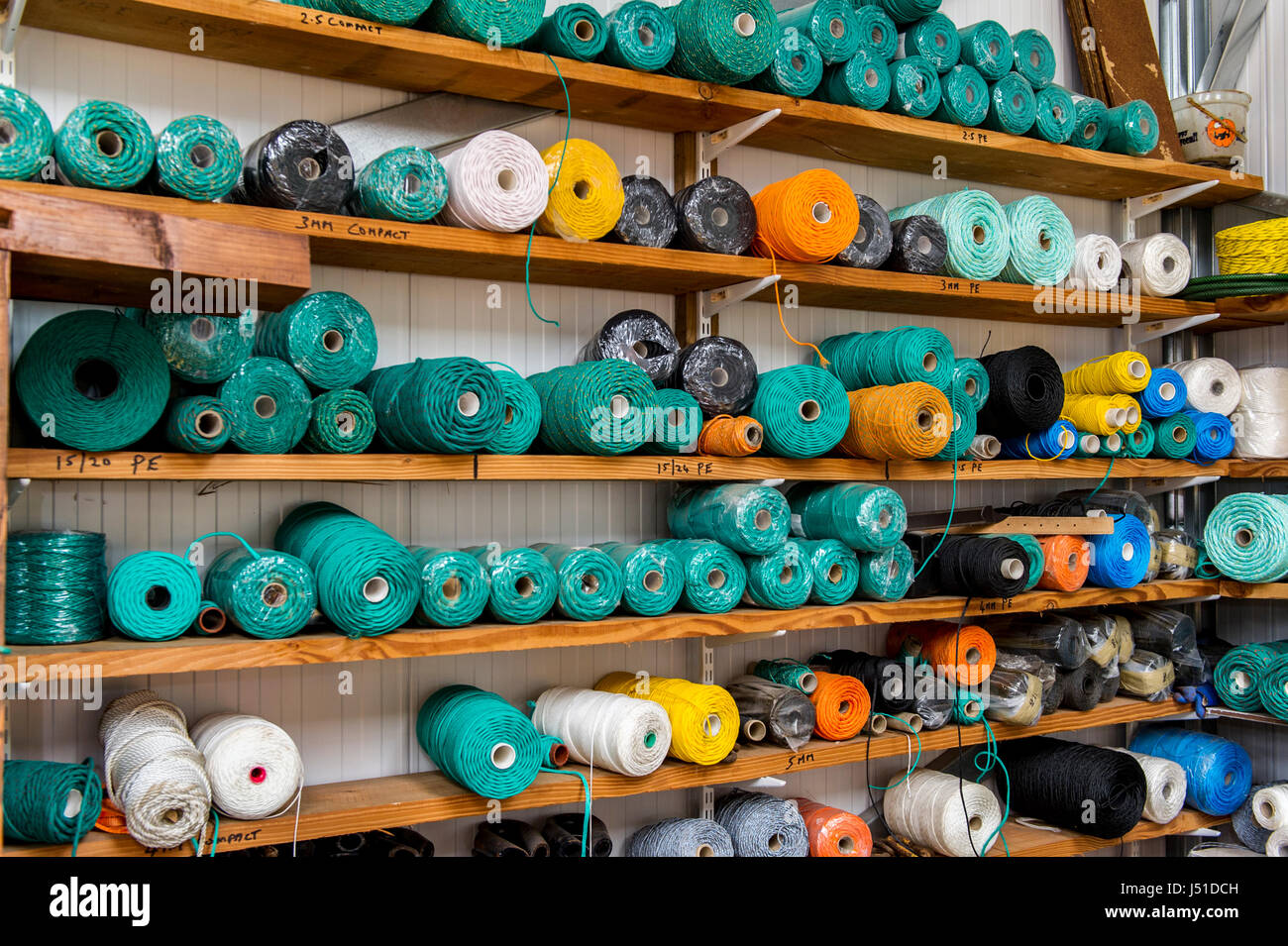 Reels of ropes and materials on shelves in the shed of a fishing net maker. Stock Photo