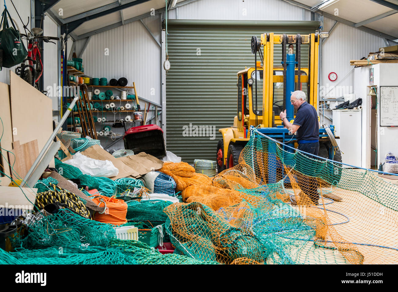 Fishing net maker makes a commercial fishing net for a trawler in his shed in Ireland with copy space. Stock Photo