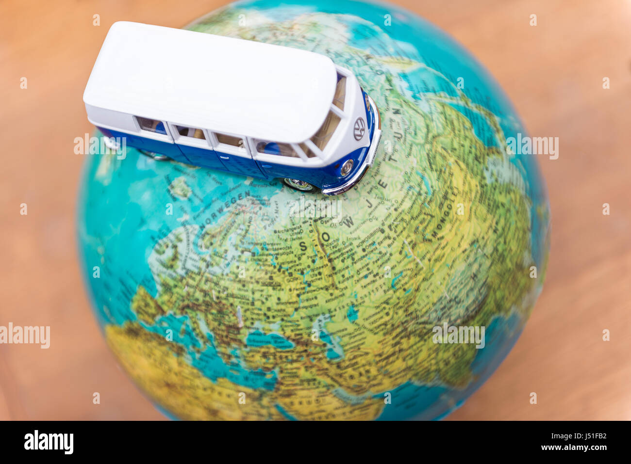 Concept of a world trip with globe and Volkswagen T1 Transporter van driving over the planet Stock Photo