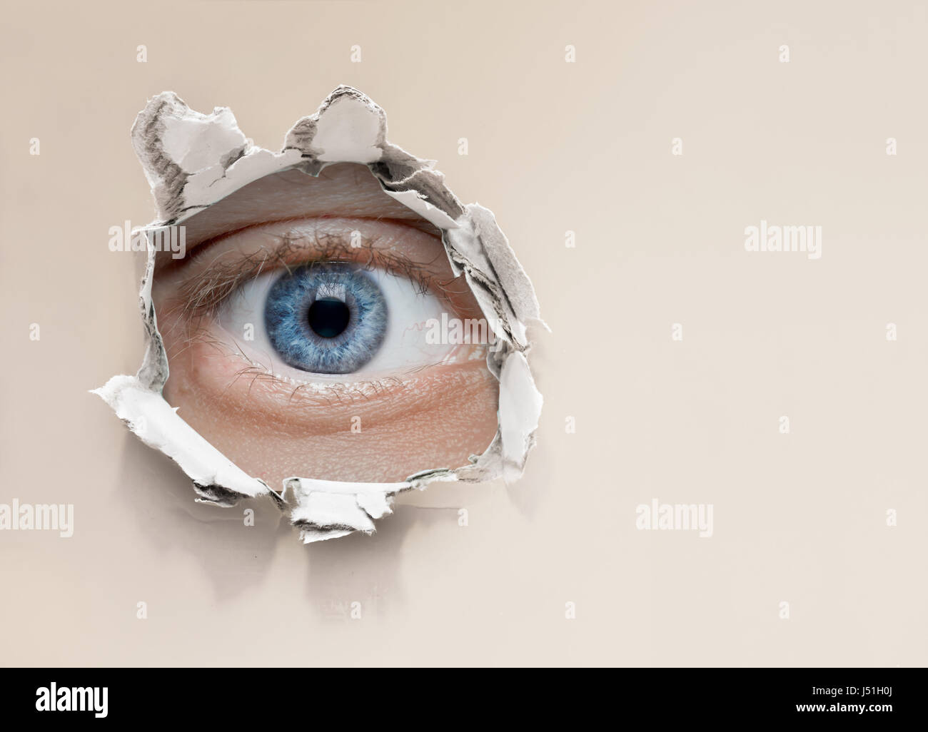 eye looking through hole in wall Stock Photo