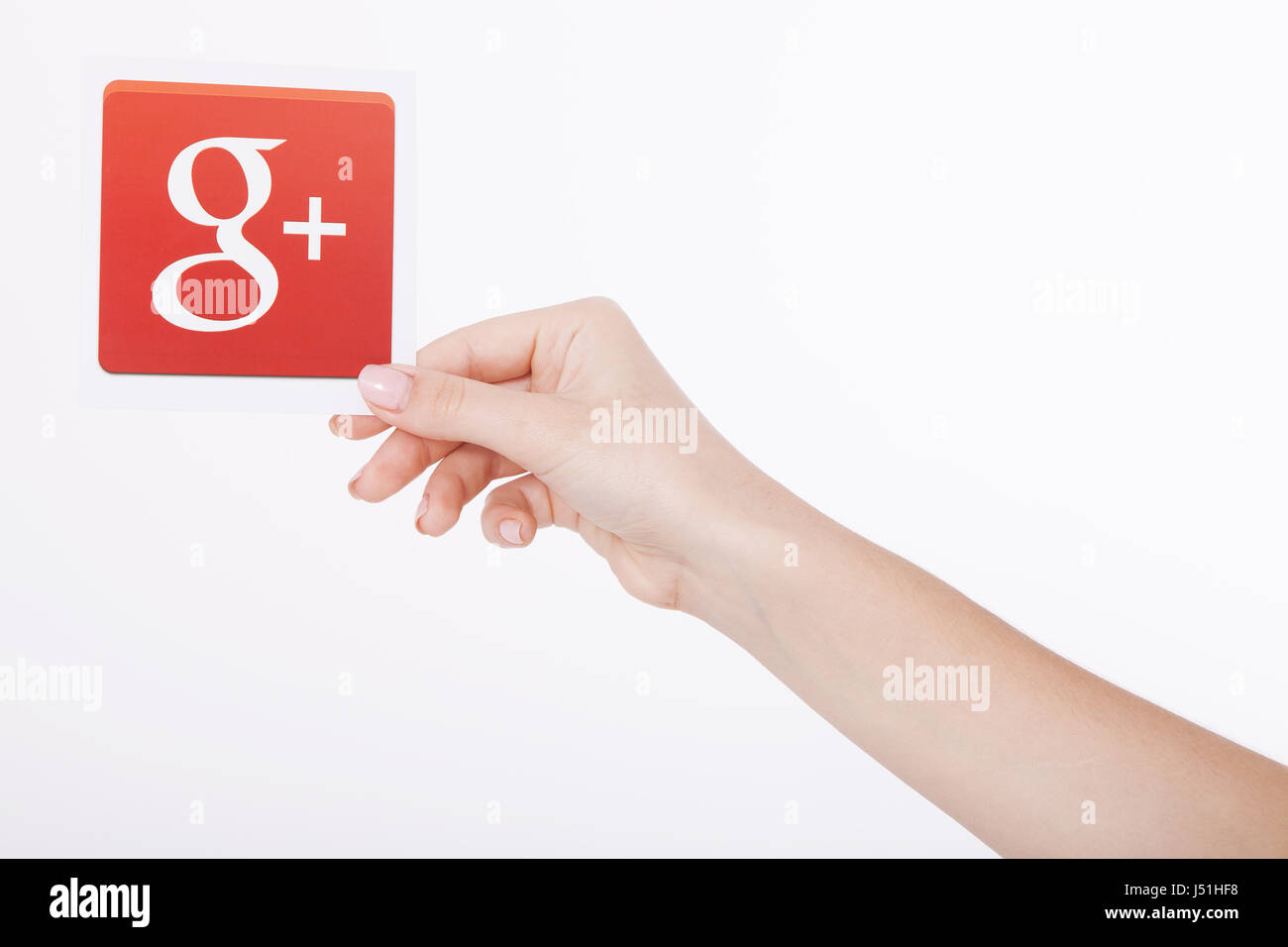 Kiev, Ukraine - August 22, 2016: Woman hands holding Google plus icon printed on paper on grey background.Google is USA multinational corporation. Stock Photo