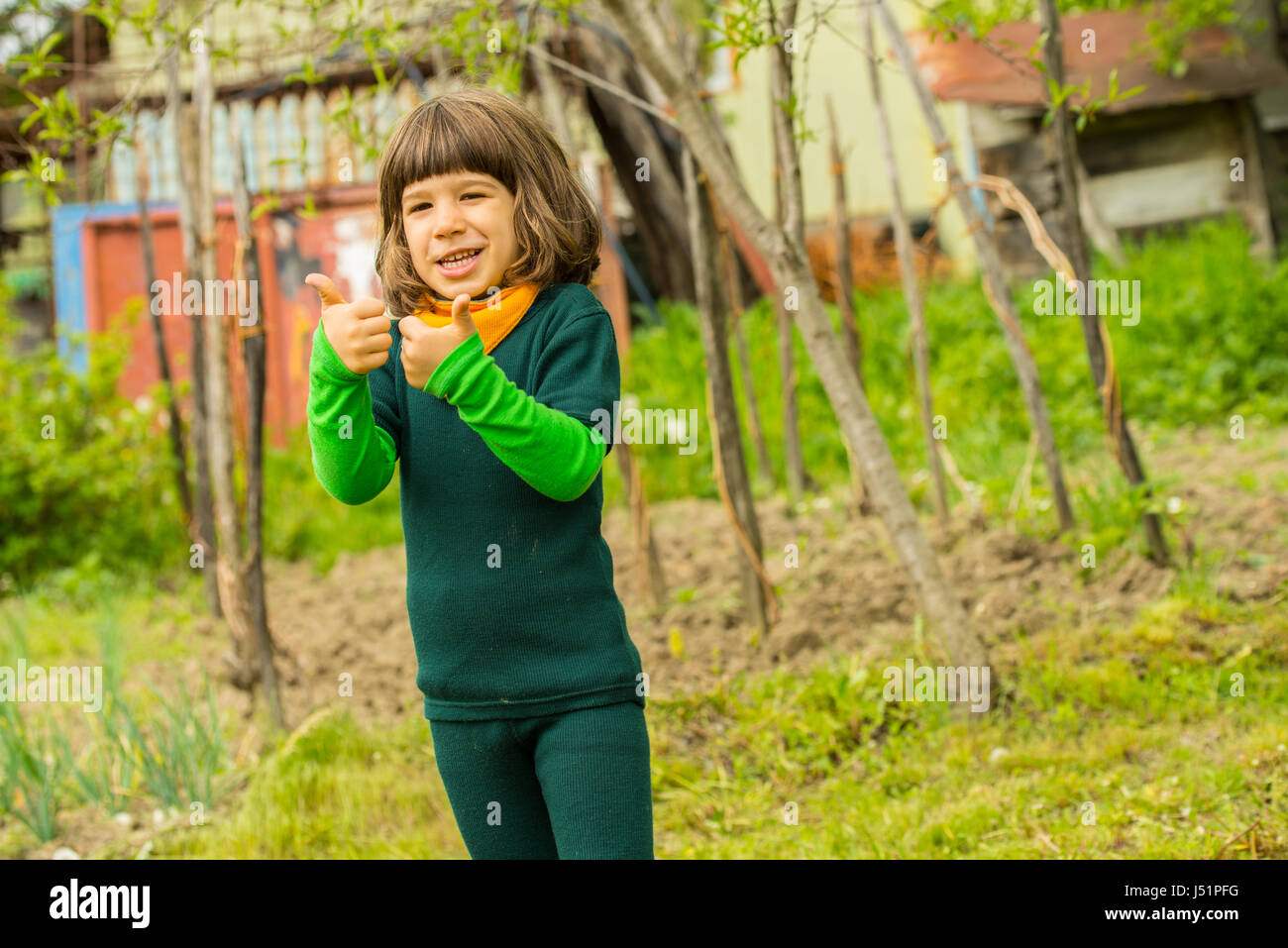 Cheerful boy in garden giving thumbs and smiling Stock Photo - Alamy