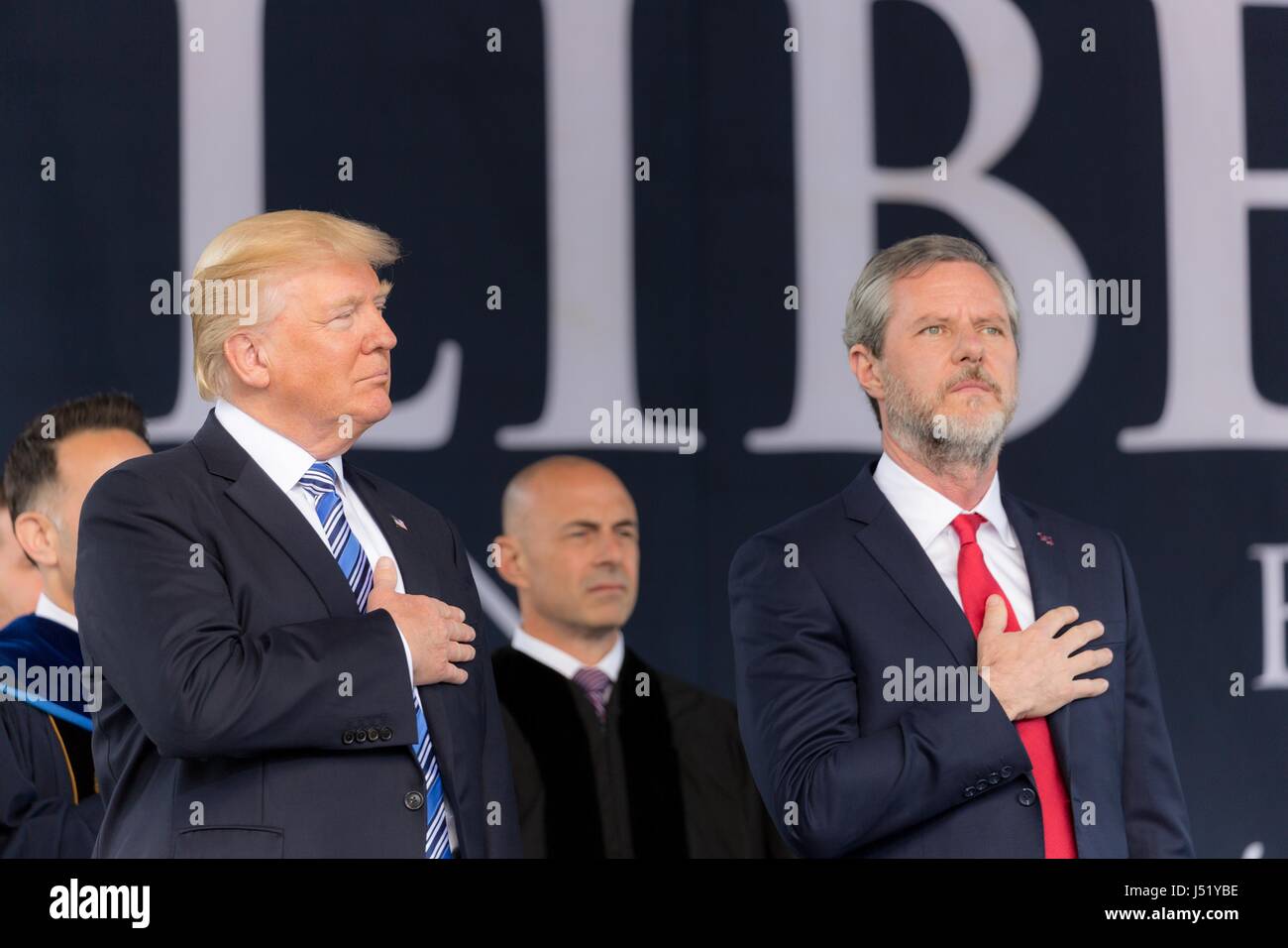 U.S. President Donald Trump stands for the national anthem alongside Liberty University President Jerry Falwell Jr., right, during the graduating class commencement ceremony May 13, 2017 in Lynchburg, Virginia. Stock Photo