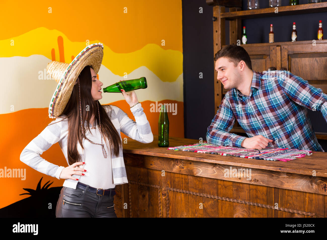 A young woman in a sombrero drinking a 