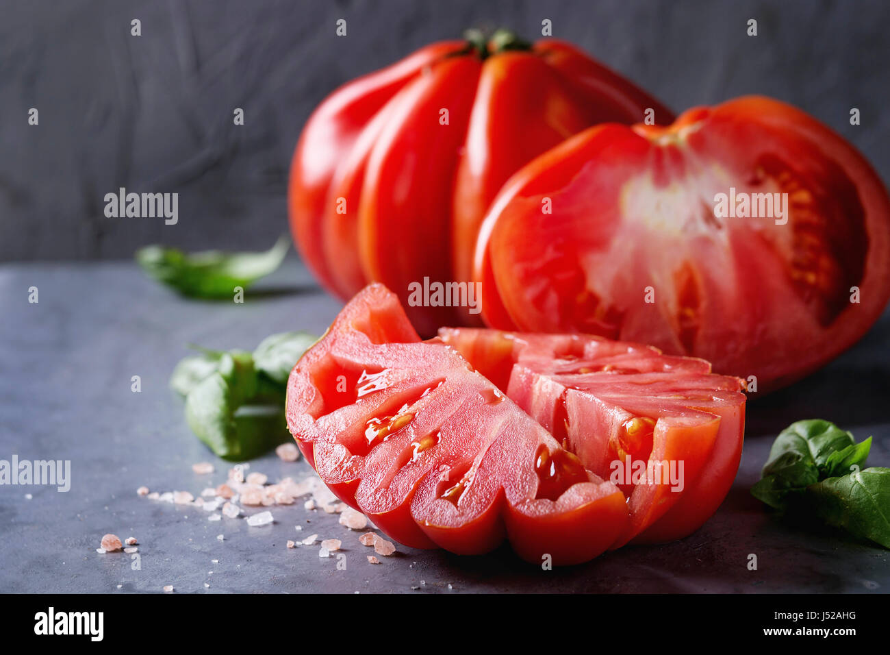 Whole and sliced organic tomatoes Coeur De Boeuf. Beefsteak tomato with