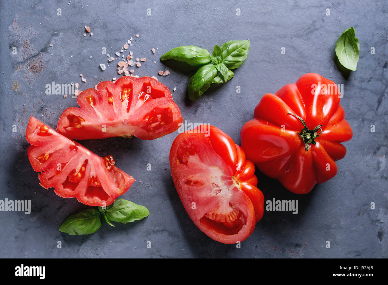 Whole and sliced organic tomatoes Coeur De Boeuf. Beefsteak tomato with