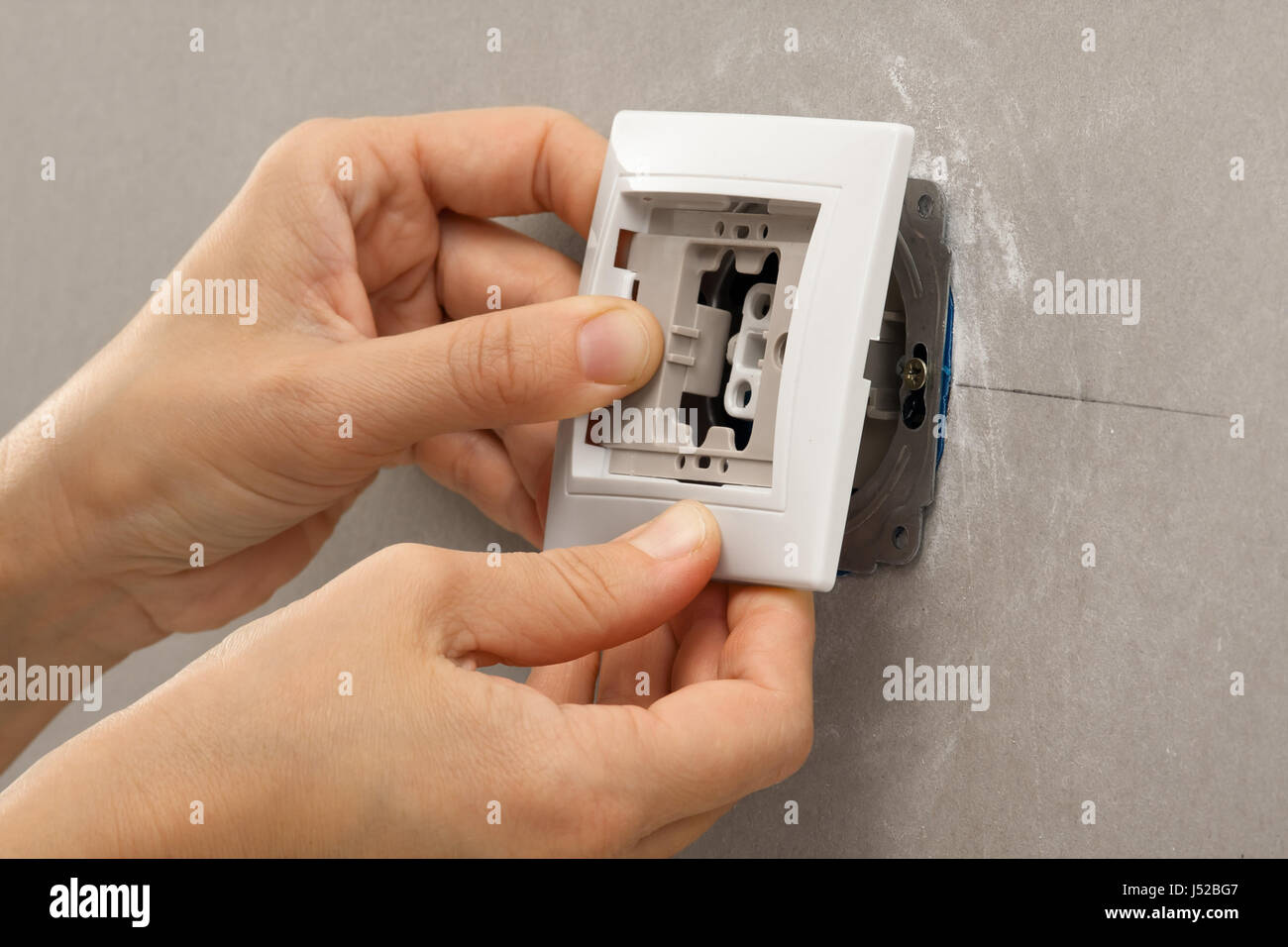 hands of electrician installing light switch on the wall from