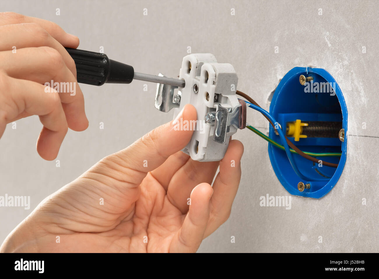 hands of electrician installing light switch with screwdriver in the wall Stock Photo