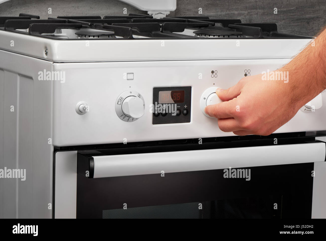 Male hand turning on white kitchen gas stove on gray background Stock Photo Alamy