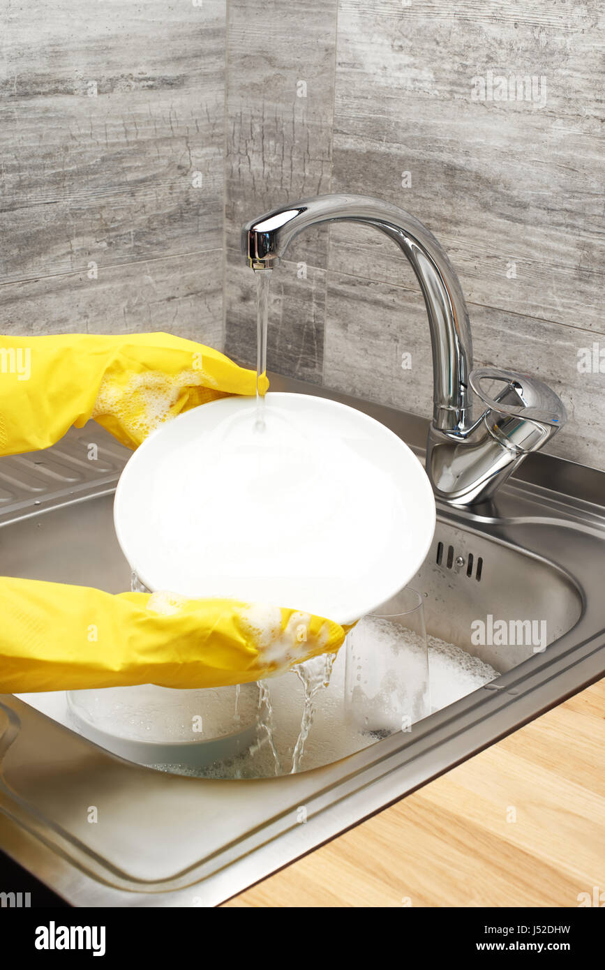 Close up of female hands in yellow protective rubber gloves washing ...