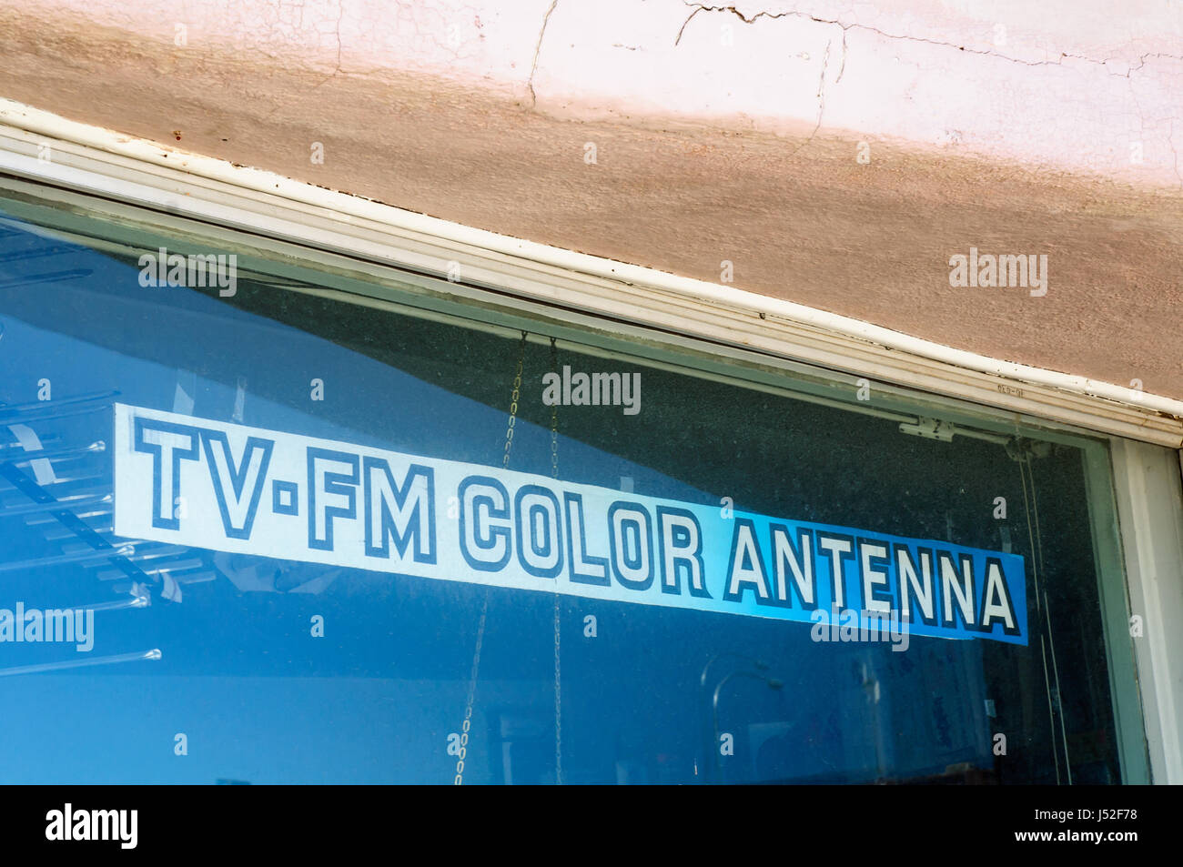 Sign advertising TV-FM COLOR ANTENNA which looks to be in 80's font in a closed down business. Stock Photo