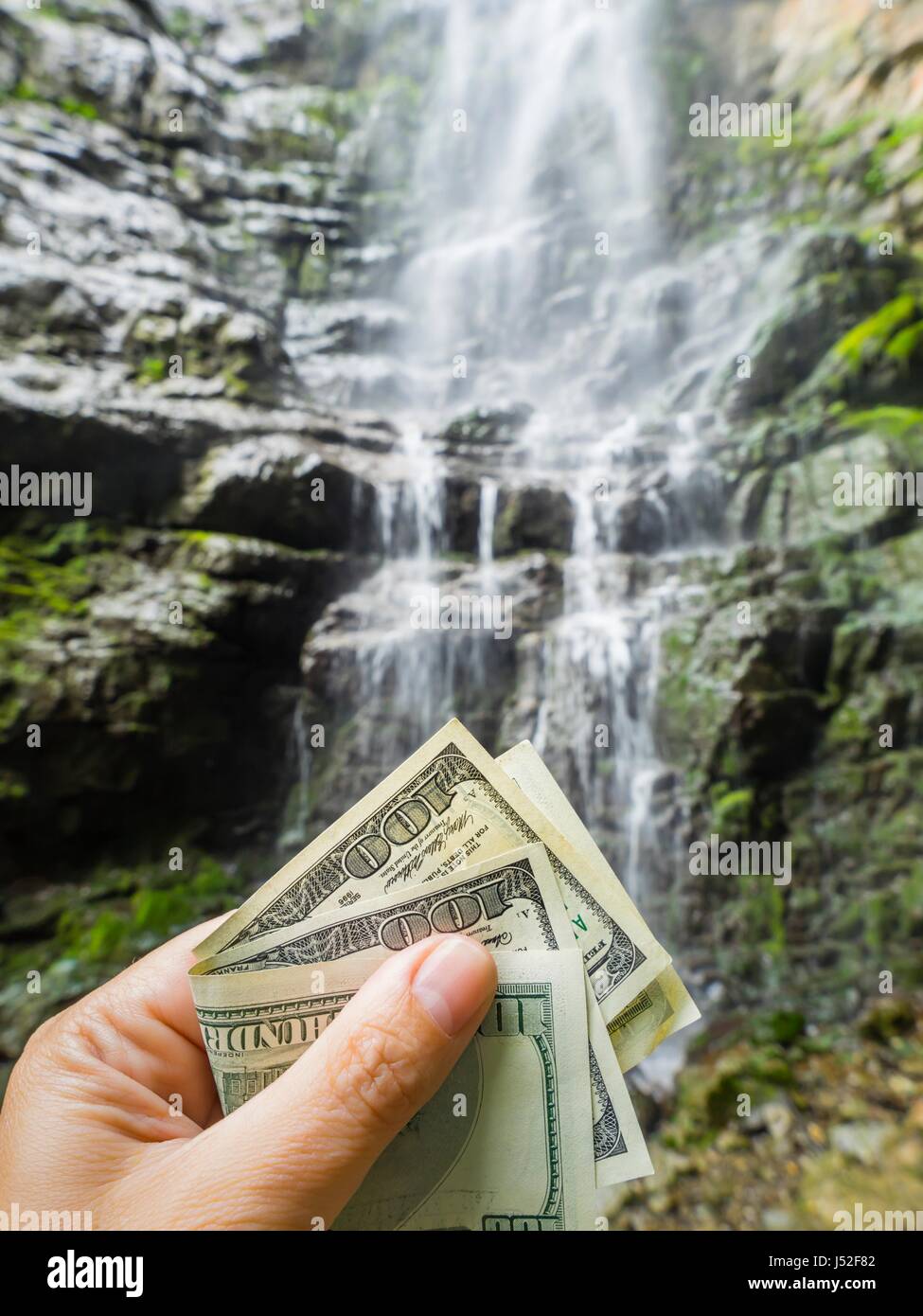 Fresh drinking water is expensive money in hand blurry background rocky terrain rocks value valuable free space price to pay pour pouring ownership Stock Photo