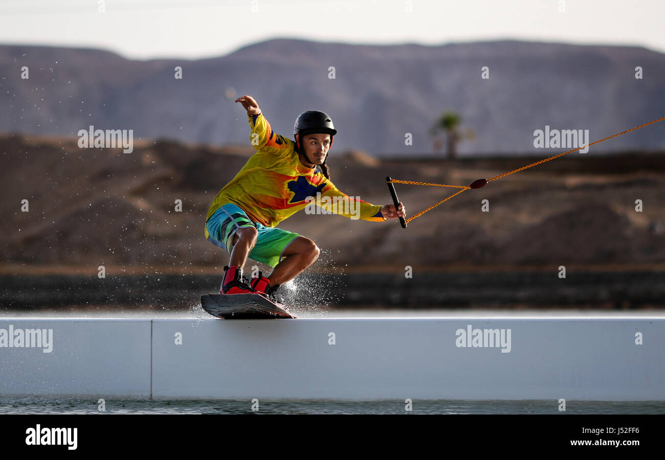 Wakeboarding sportsman rider on the slider in the wake cablepark, active sports and life style, water sport as hobby, mountains background picture Stock Photo