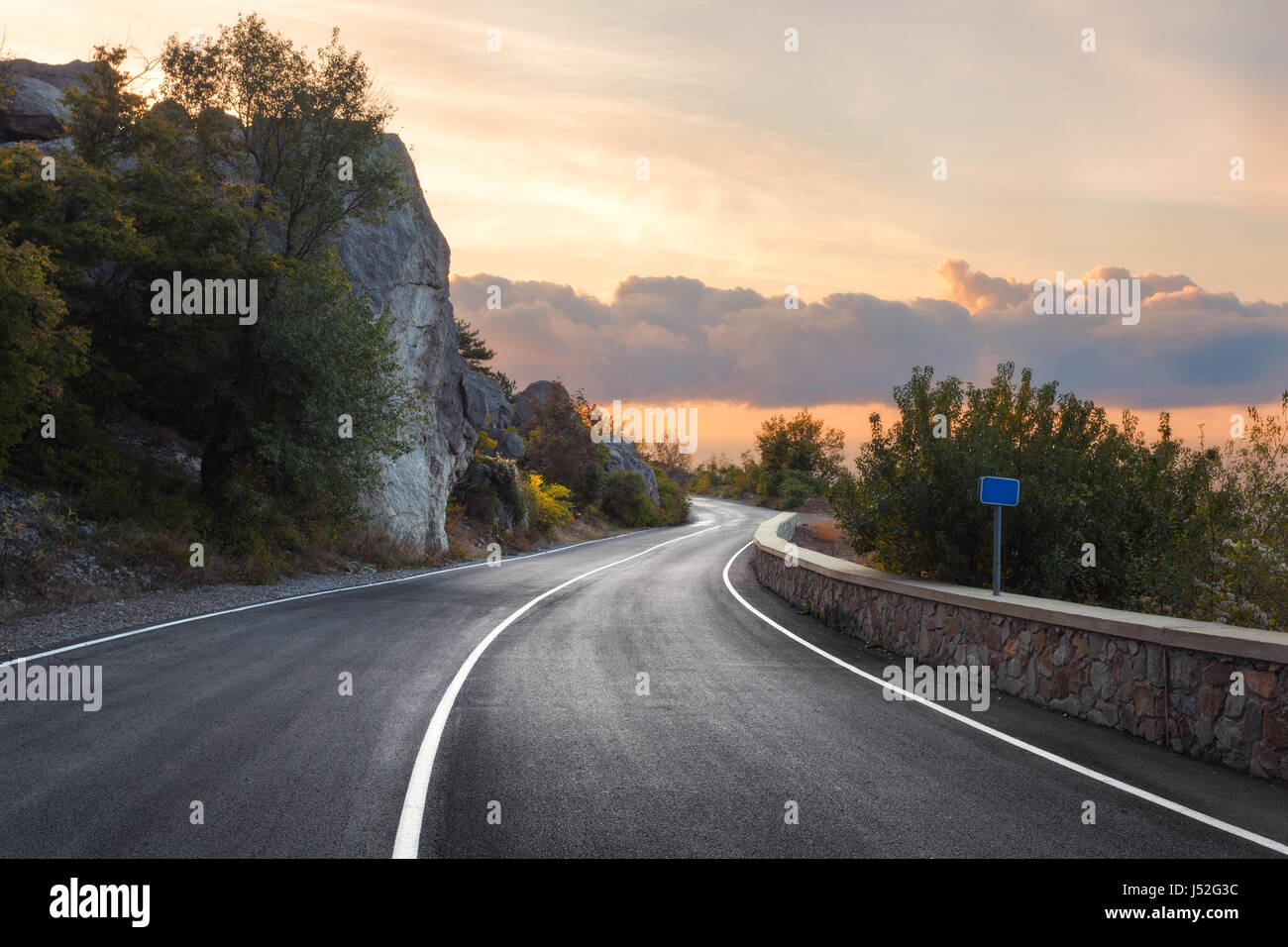 Asphalt road. Landscape with rocks, sunny sky with clouds and beautiful mountain road with a perfect asphalt at sunrise in summer. Vintage toning. Tra Stock Photo