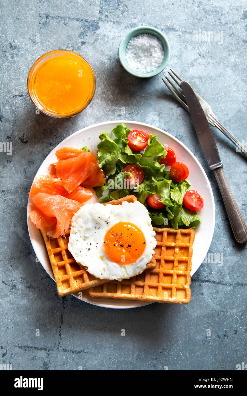 Savory waffles with smoked salmon,poached egg, salad and a glass of ...