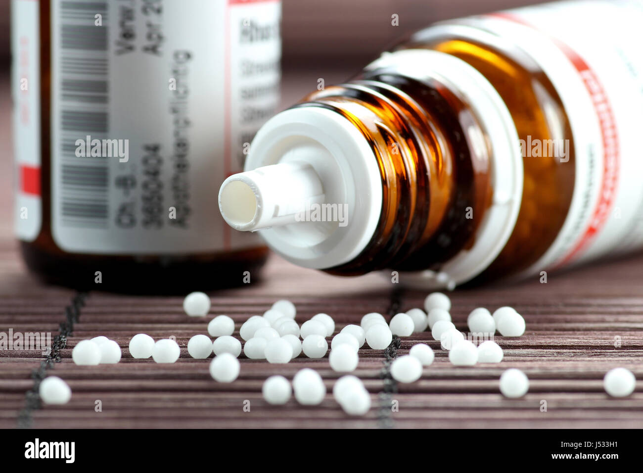scattered homeopathic pills falling out of upset vial Stock Photo