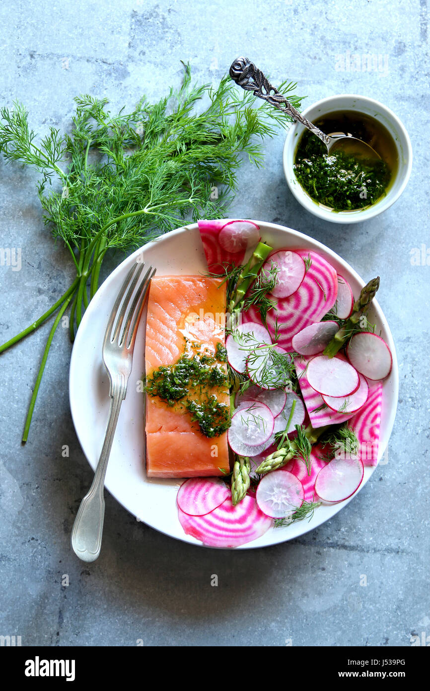 Spring salad with radish,chioggia beet,asparagus with a piece of smoked salmon and dill dressing on a plate Stock Photo