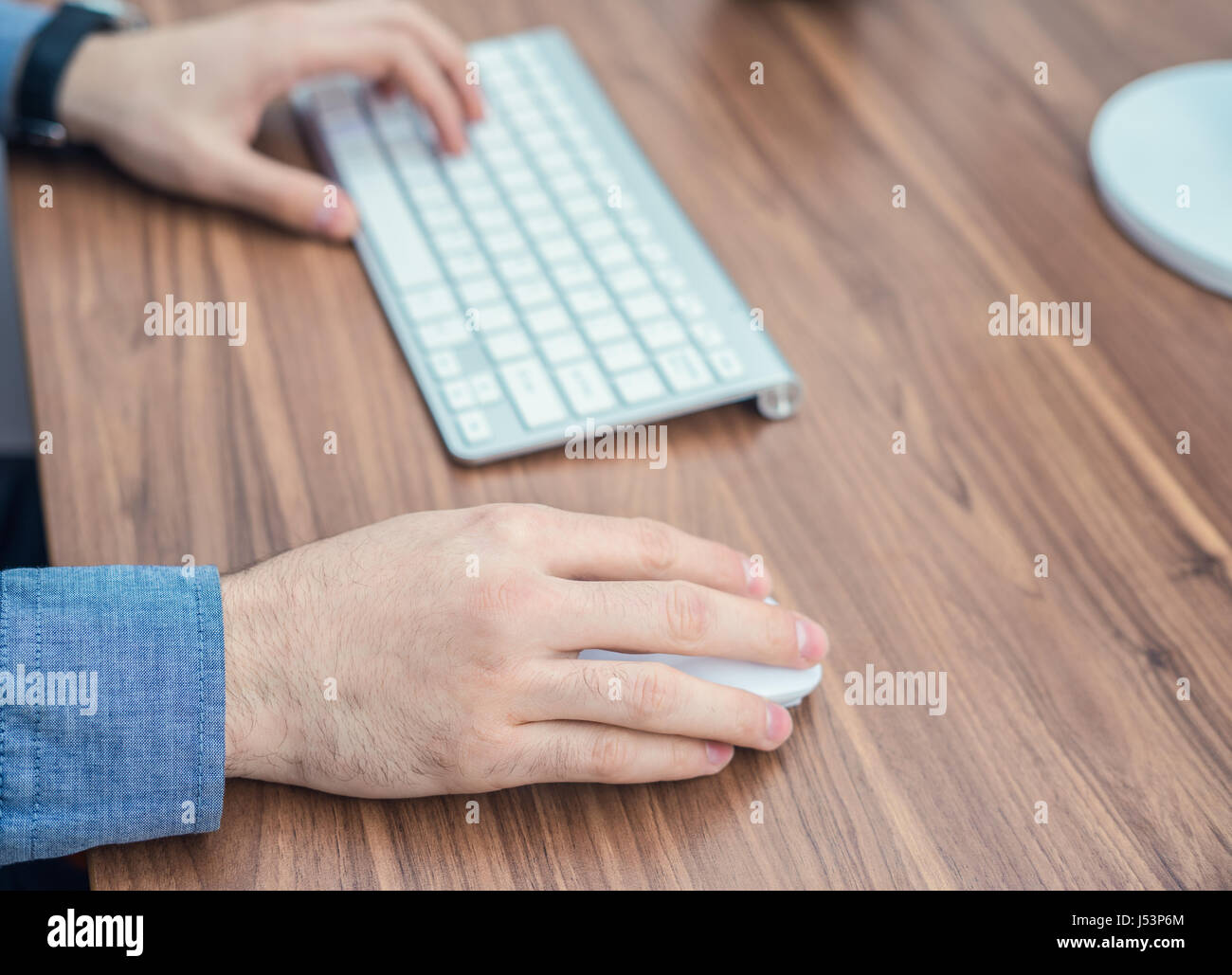 Hands typing on wireless keyboard on wooden table Stock Photo