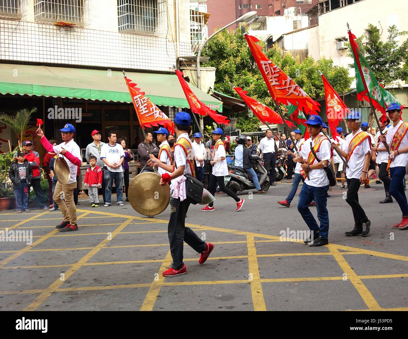KAOHSIUNG, TAIWAN -- MARCH 16, 2014: Religious devotees carry flags and beat gongs in a procession that is part of a local religious ceremony. Stock Photo