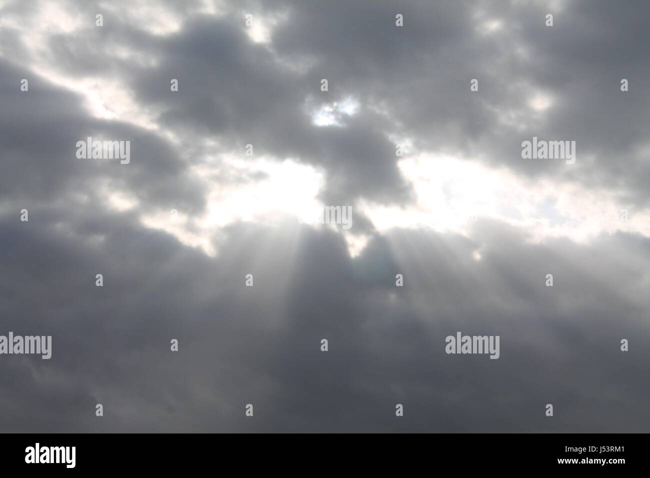 Sun rays shining through overcast sky Stock Photo