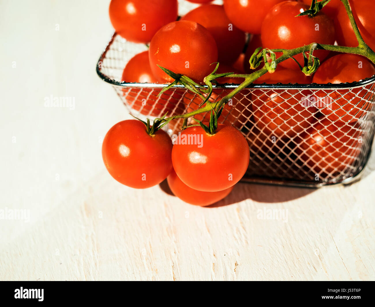 Cherry tomatoes in small metal basket Stock Photo - Alamy