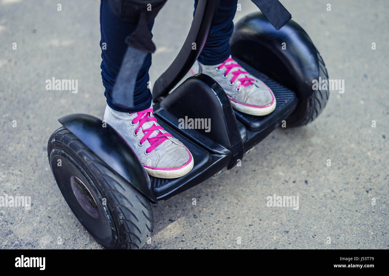 girl's legs wearing sneakers riding gyroscooter or hoverboard Stock Photo