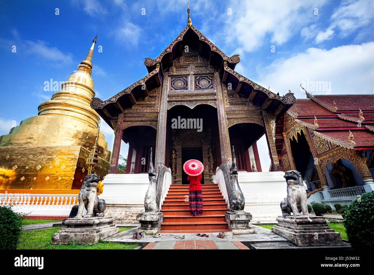 Woman tourist with red traditional Thai umbrella near Golden temple Wat Phra Singh in Chiang Mai, Thailand Stock Photo