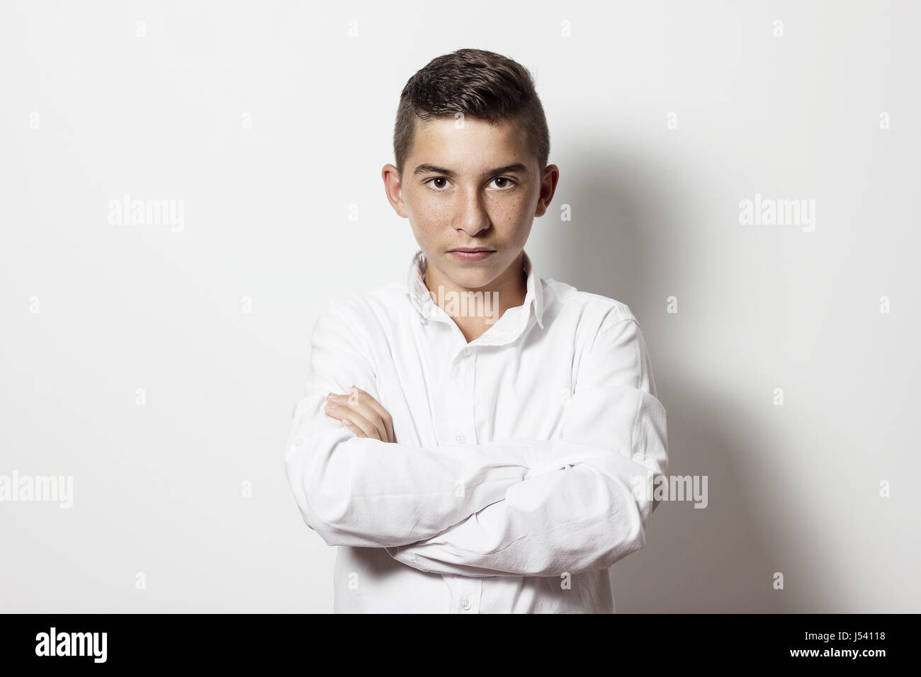 serious cute boy with crossed arms in front of white background Stock Photo